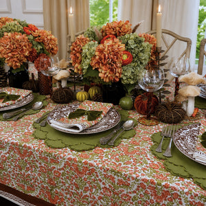 A hand block printed tablecloth, featuring a floral pumpkin and sage green floral pattern on a white background, finished with a brown band and Greek key border at the bottom, Thanksgiving tablecloth, luxury table linens