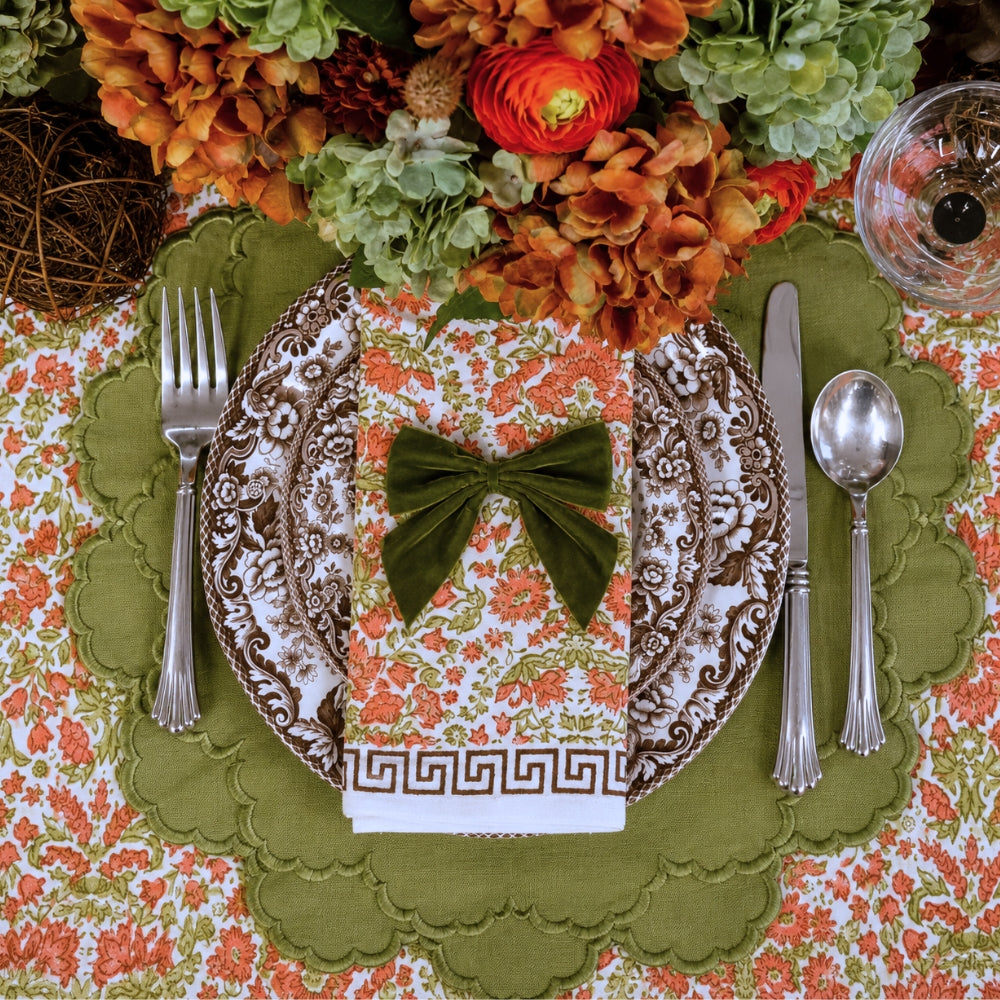 A hand block printed tablecloth, featuring a floral pumpkin and sage green floral pattern on a white background, finished with a brown band and Greek key border at the bottom, Thanksgiving tablecloth, luxury table linens