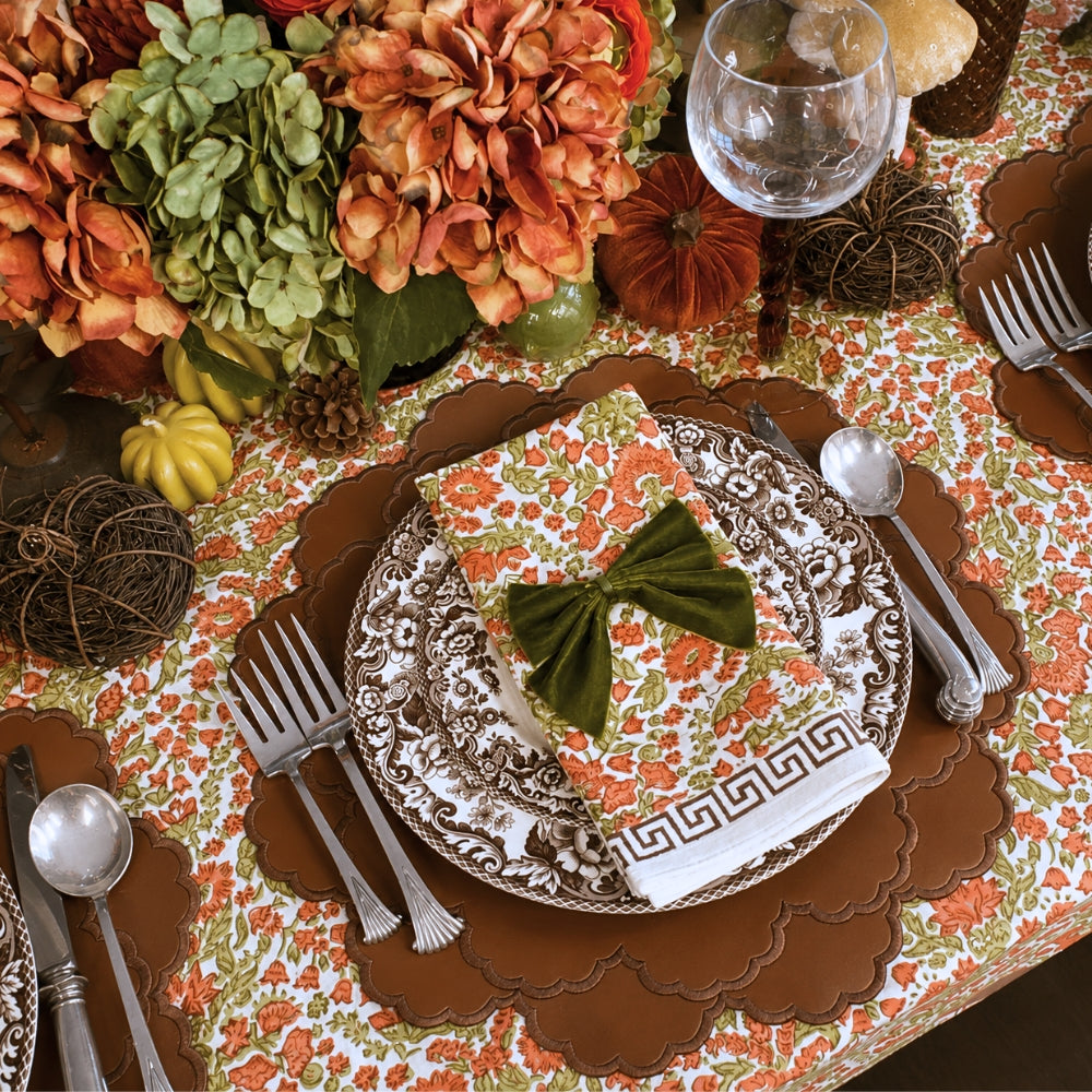 A hand block printed tablecloth, featuring a floral pumpkin and sage green floral pattern on a white background, finished with a brown band and Greek key border at the bottom, Thanksgiving tablecloth, luxury table linens