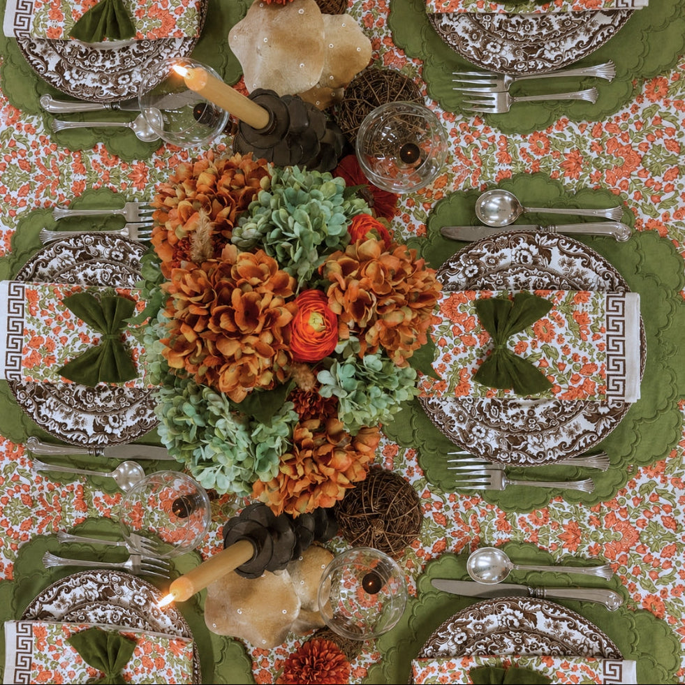 A hand block printed tablecloth, featuring a floral pumpkin and sage green floral pattern on a white background, finished with a brown band and Greek key border at the bottom, Thanksgiving tablecloth, luxury table linens