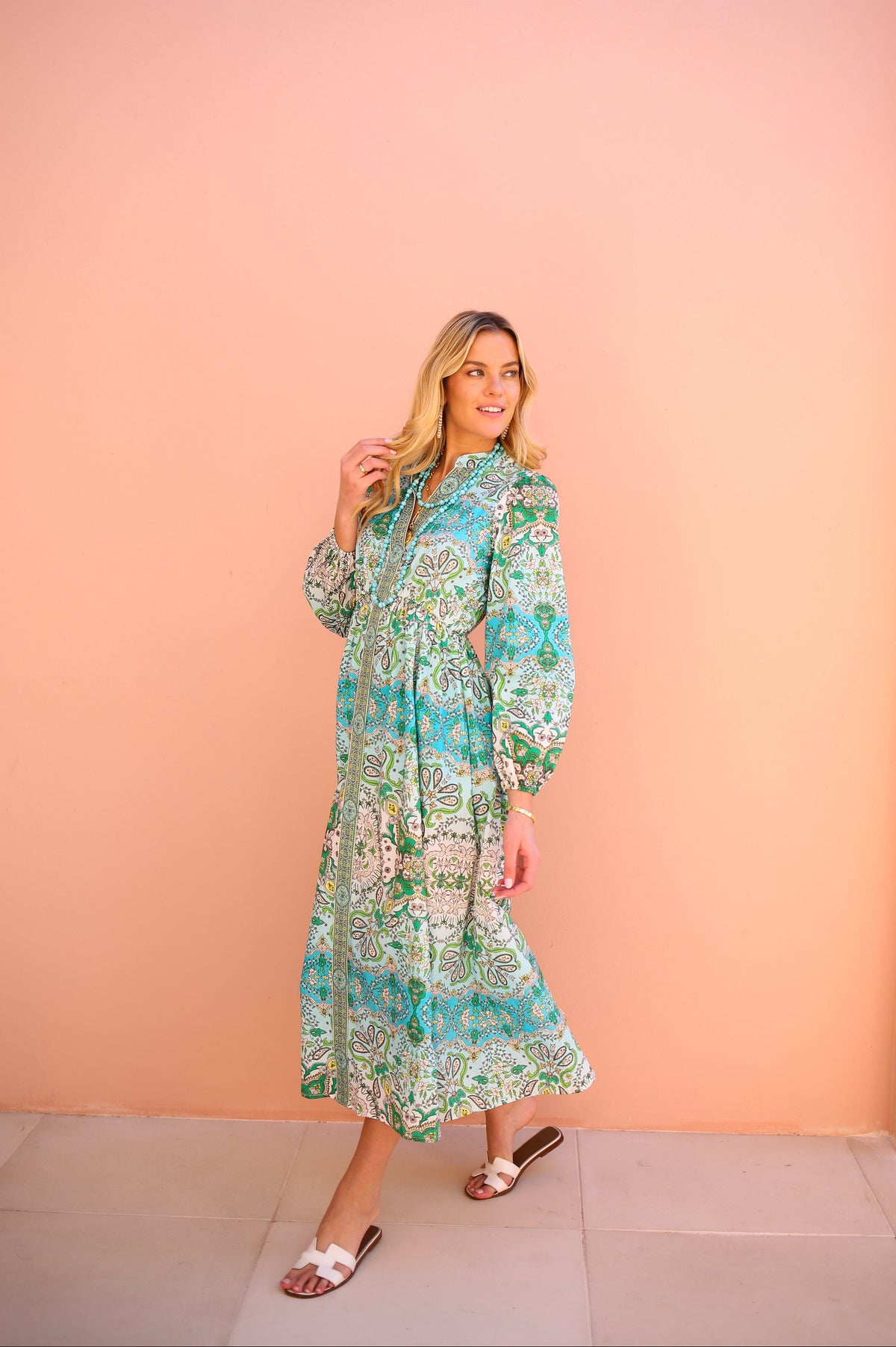 Woman wearing a floral dress against a peach-colored wall