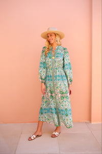 Woman wearing a floral dress and hat against a pink wall