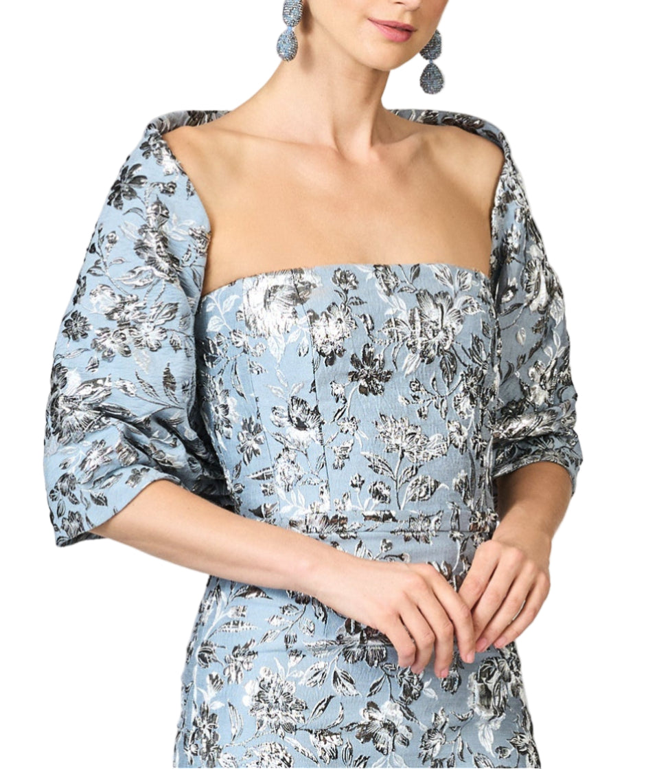 Front three-quarter of Metallic Cloque Hug Shawl draped over model’s shoulders, silver floral metallic texture on pale blue