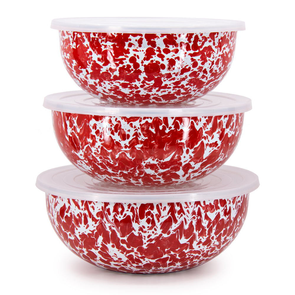 Front view of set of three red swirl enamel mixing bowls with removable white lids stacked on a white background