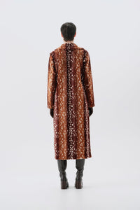 Model pictured from the back wearing a long brown faux fur coat with a bambi pattern on a white background