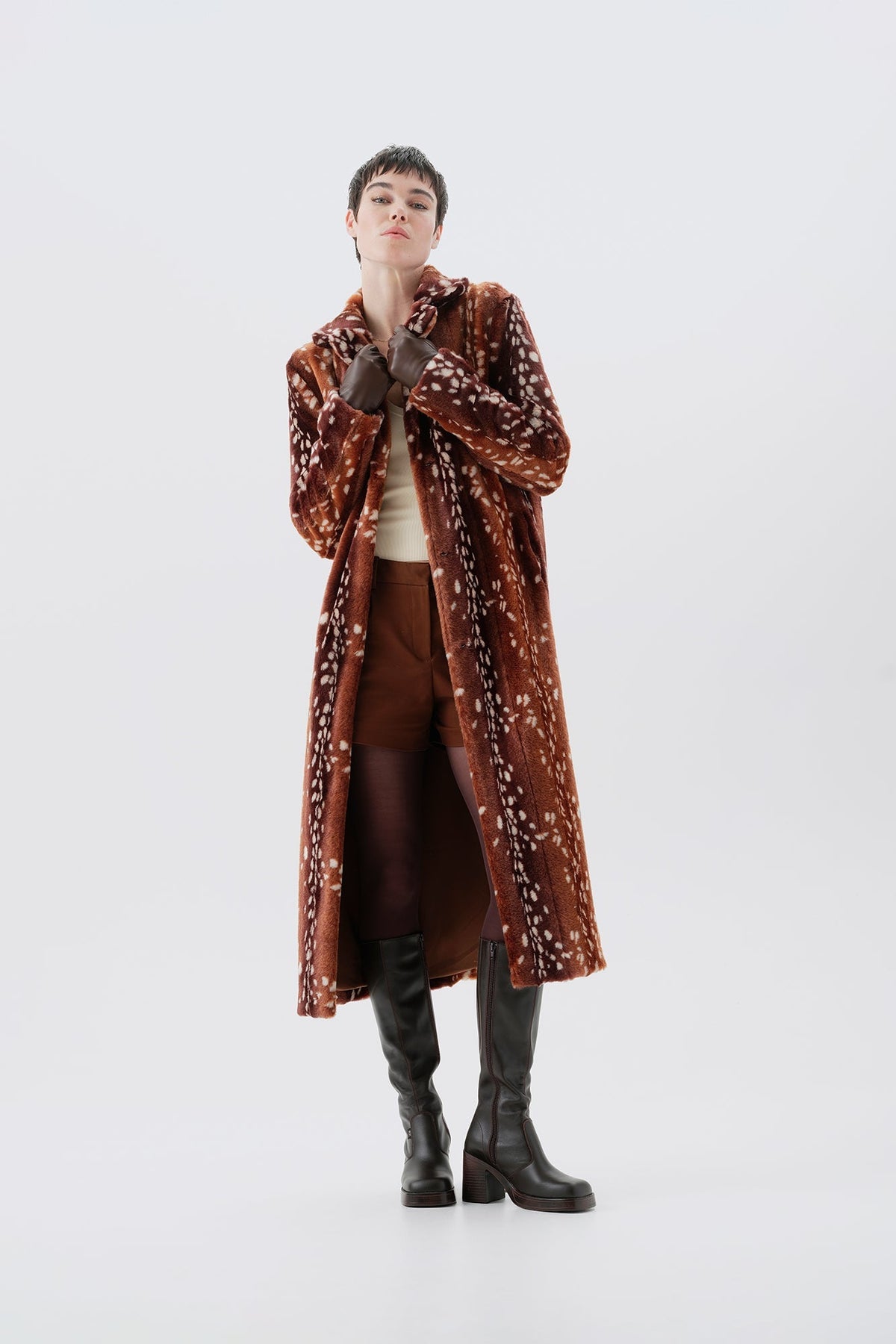 Model wearing a long brown faux fur coat with a bambi pattern on a white background