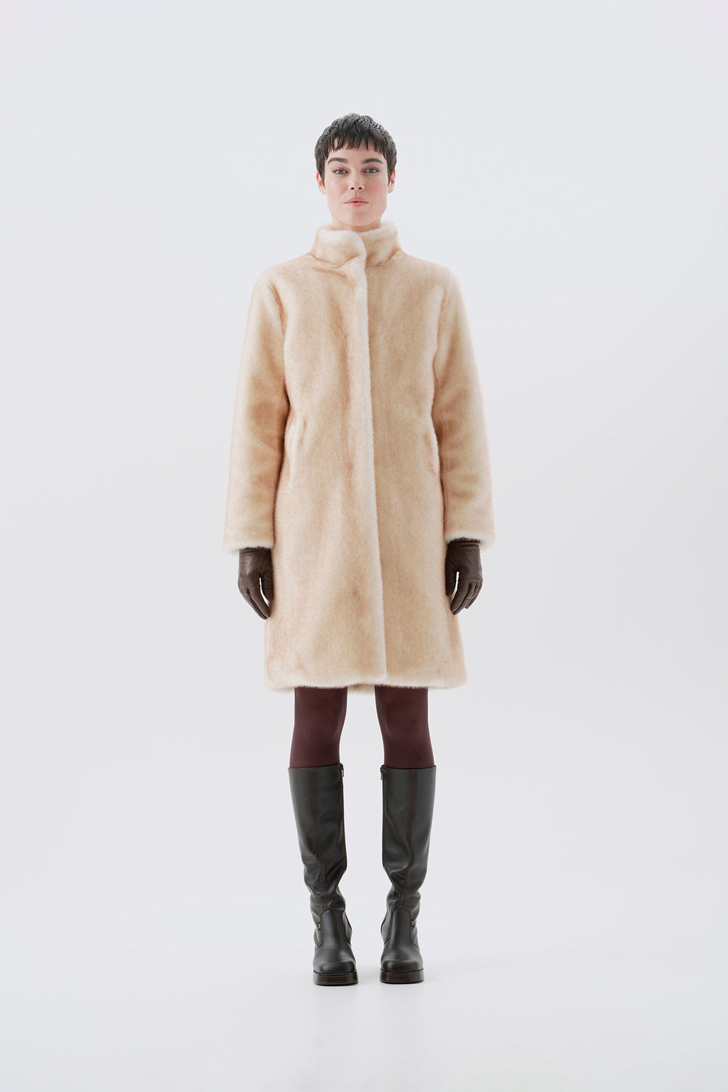 Model wearing a beige faux fur coat, dark pants, and black boots