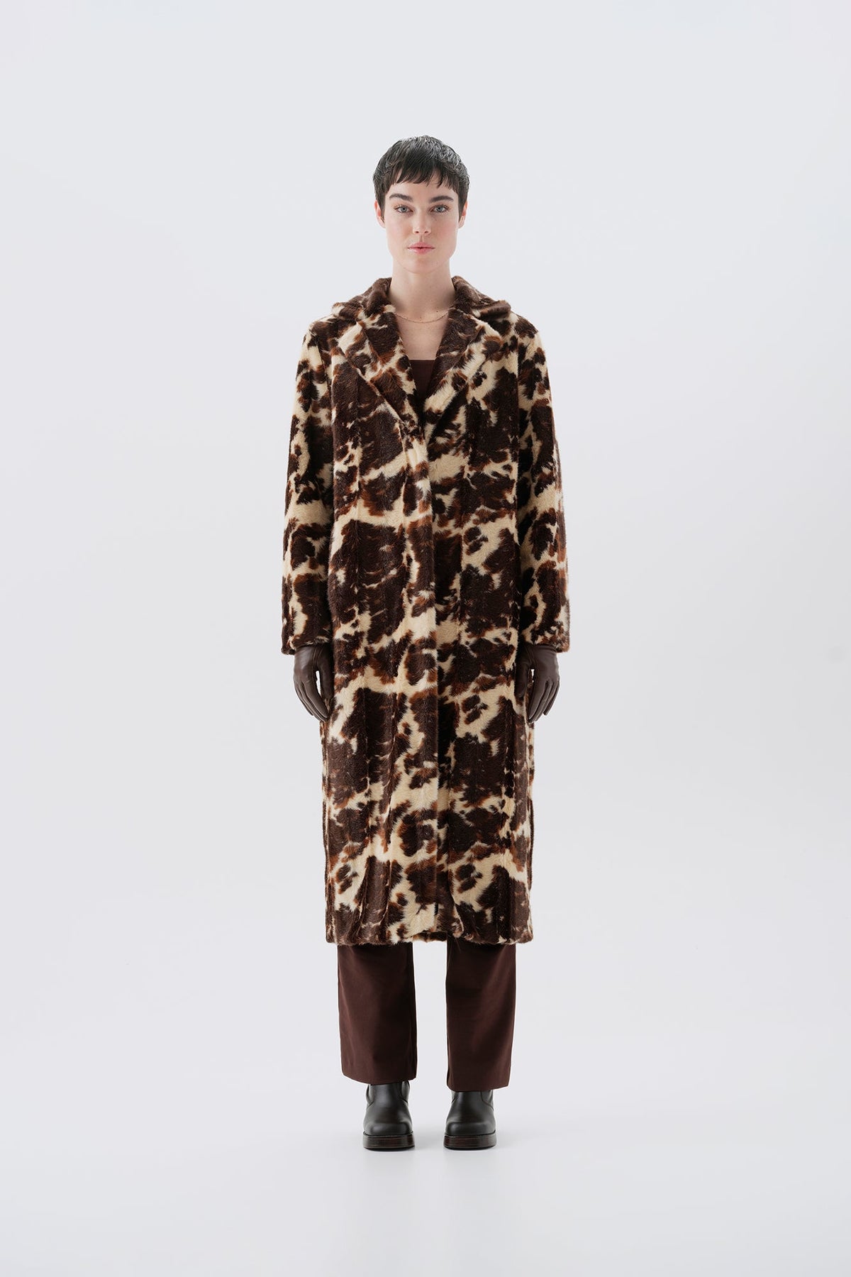 Model wearing a faux fur cow print long coat on a white background