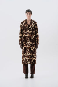 Model wearing a faux fur cow print long coat on a white background