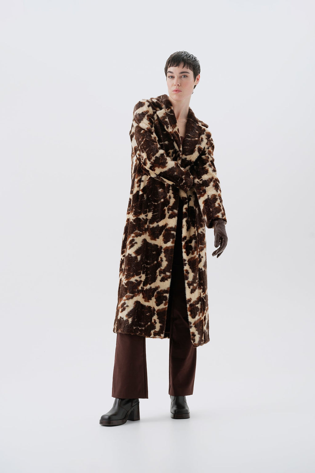 Model wearing a faux fur cow print long coat on a white background
