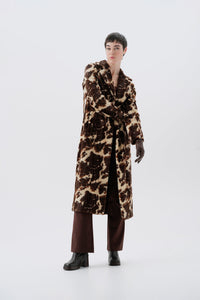 Model wearing a faux fur cow print long coat on a white background