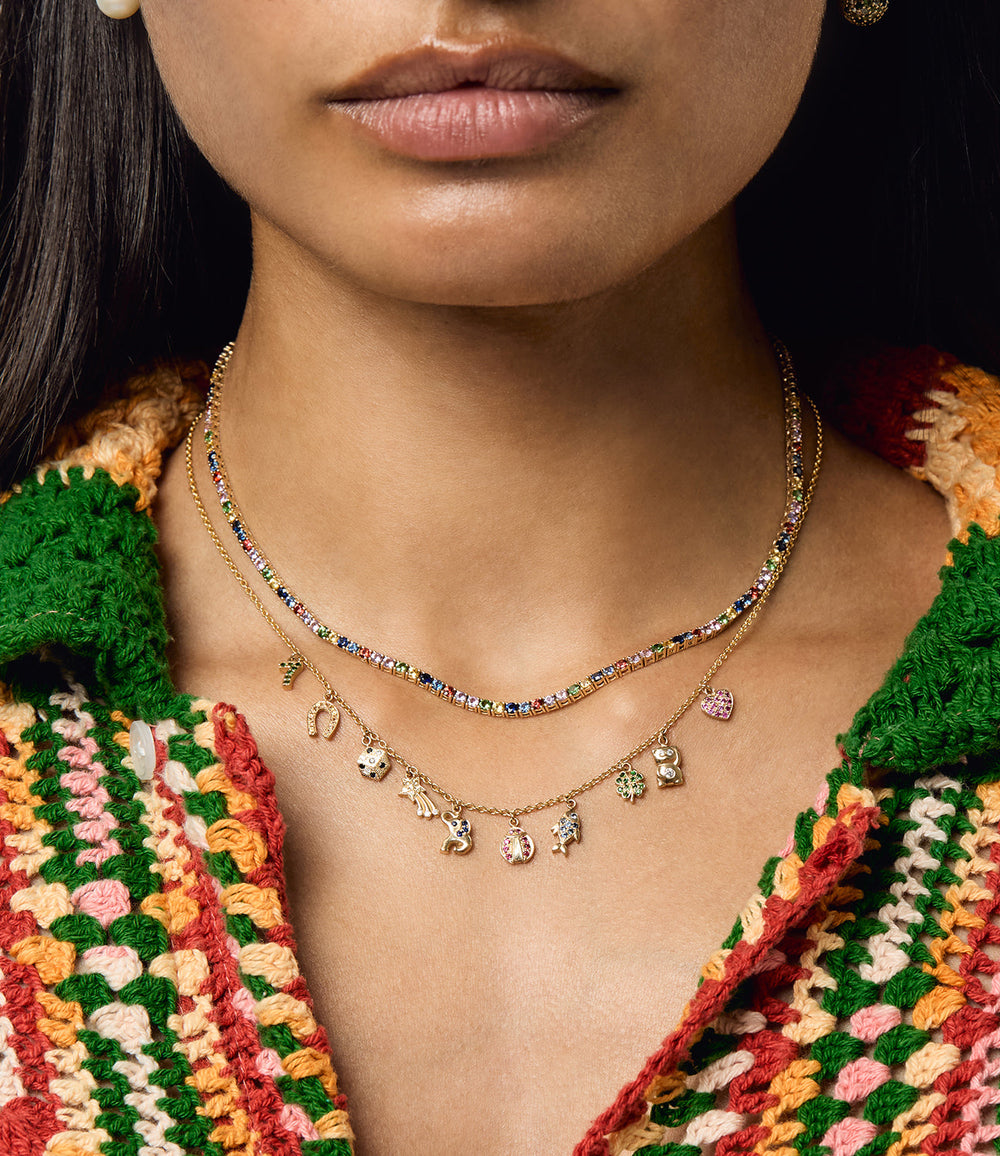 Close-up of Rainbow Sapphire All The Luck Charm Necklace showing a rainbow sapphire chain layered with a gold charm chain of small lucky charms
