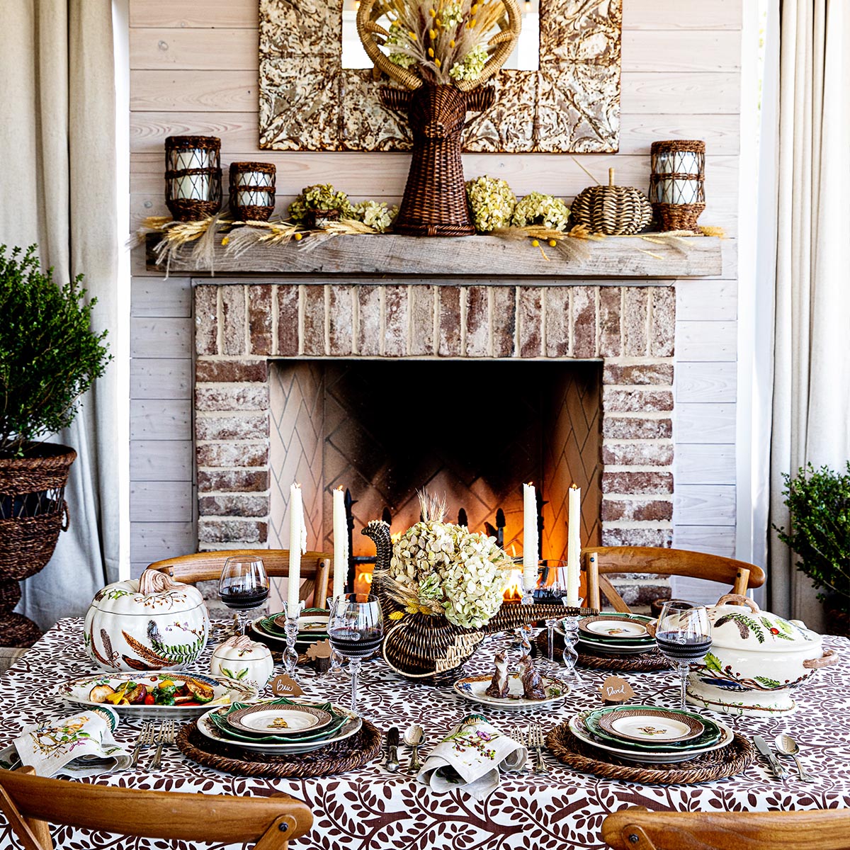 Small woven Devon Willow pumpkin on a fall table setting with plates, candles, and a lit fireplace in the background