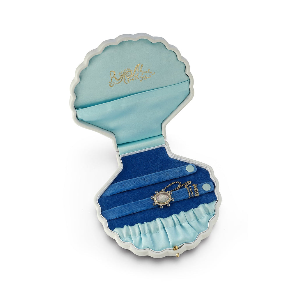 Top view of Large Shell jewelry box open showing light-blue silk lid with gold logo and blue velvet ring rolls on white