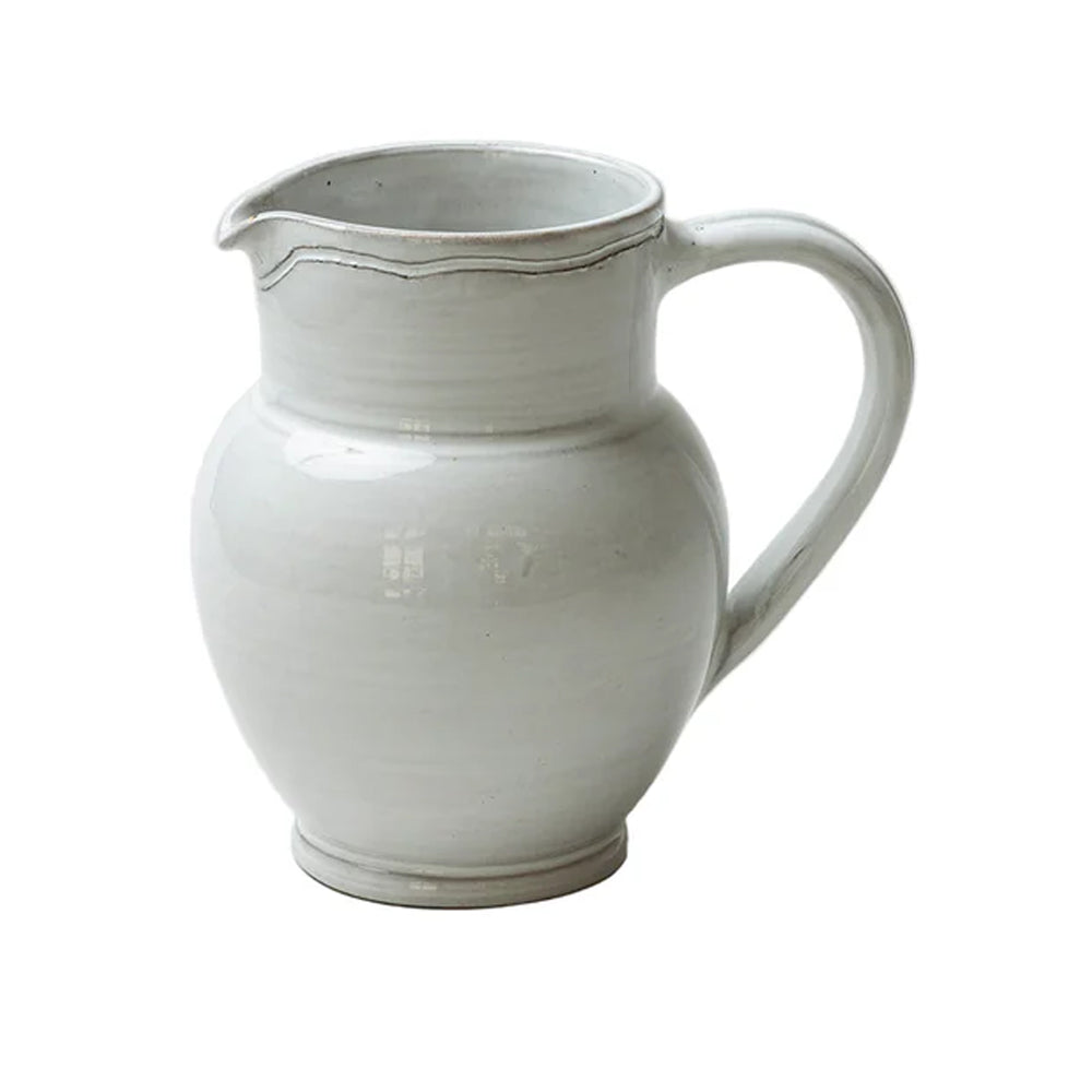 Three-quarter view of Radi Simple Pitcher showing rounded stoneware body, curved handle and spout, smooth off-white glaze