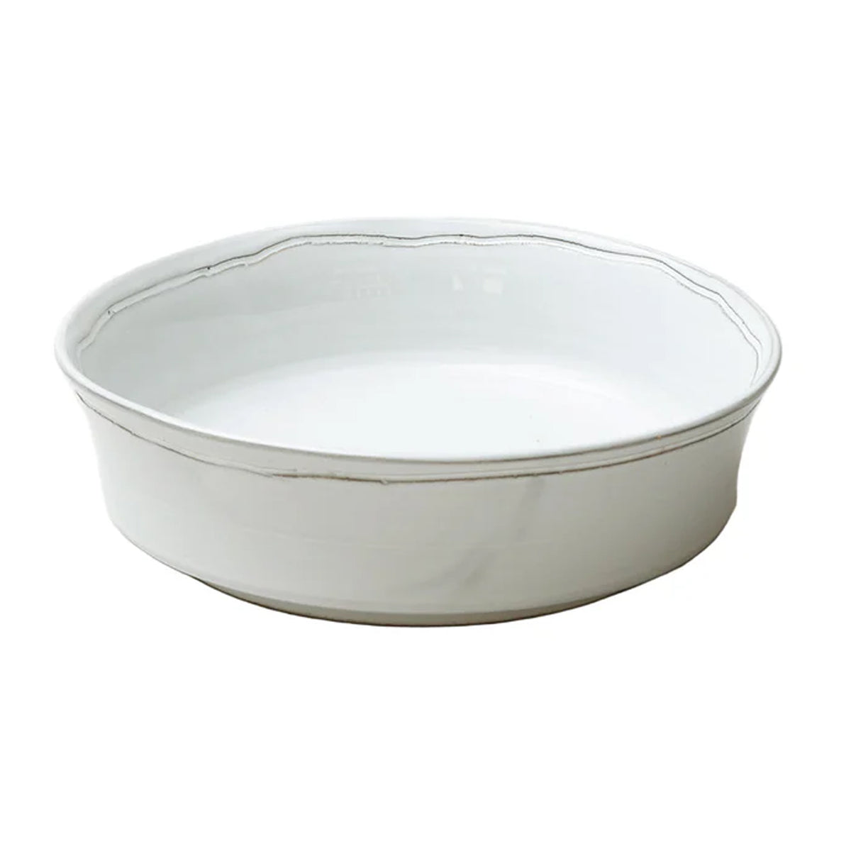 Angled view of Radi Simple serving dish showcasing smooth white glazed finish and scalloped rim on white background