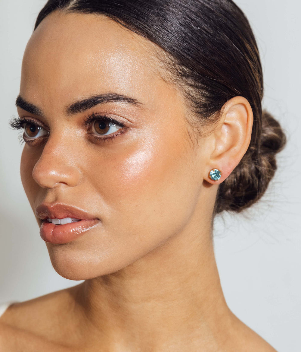 Close-up side view of model wearing Rainbow Bright stud set showing aqua crystal stud against a light neutral background