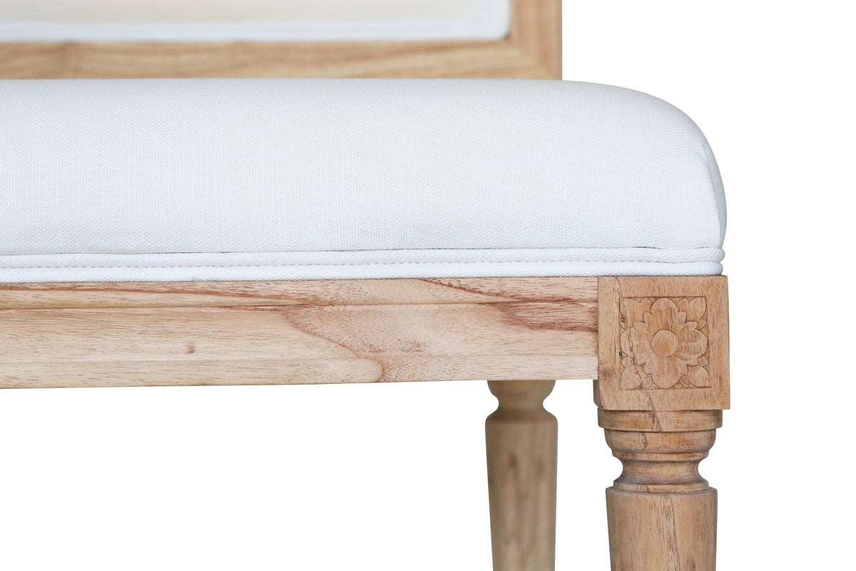 Close up view of Bienville Chair showing white linen seat and light oak frame with carved floral leg detail on white background