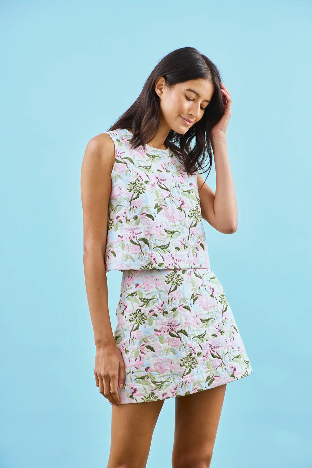 The Britt Mini Skirt in Magnolia Grove Jacquard paired with the Rebecca Top with blue background.
