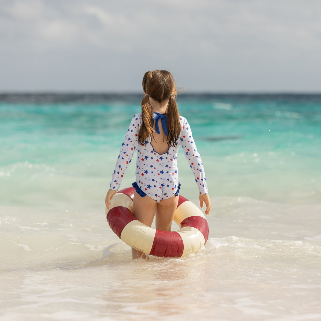 Henry Duvall Reese girls rashguard one piece in red white and blue star print, UPF 50+ long sleeve swimsuit for 4th of July, beach, and summer holidays