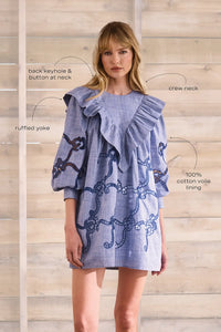 Blue cut-out embroidered linen, crew neckline, softly ruffled yoke, long sleeves with button cuffs