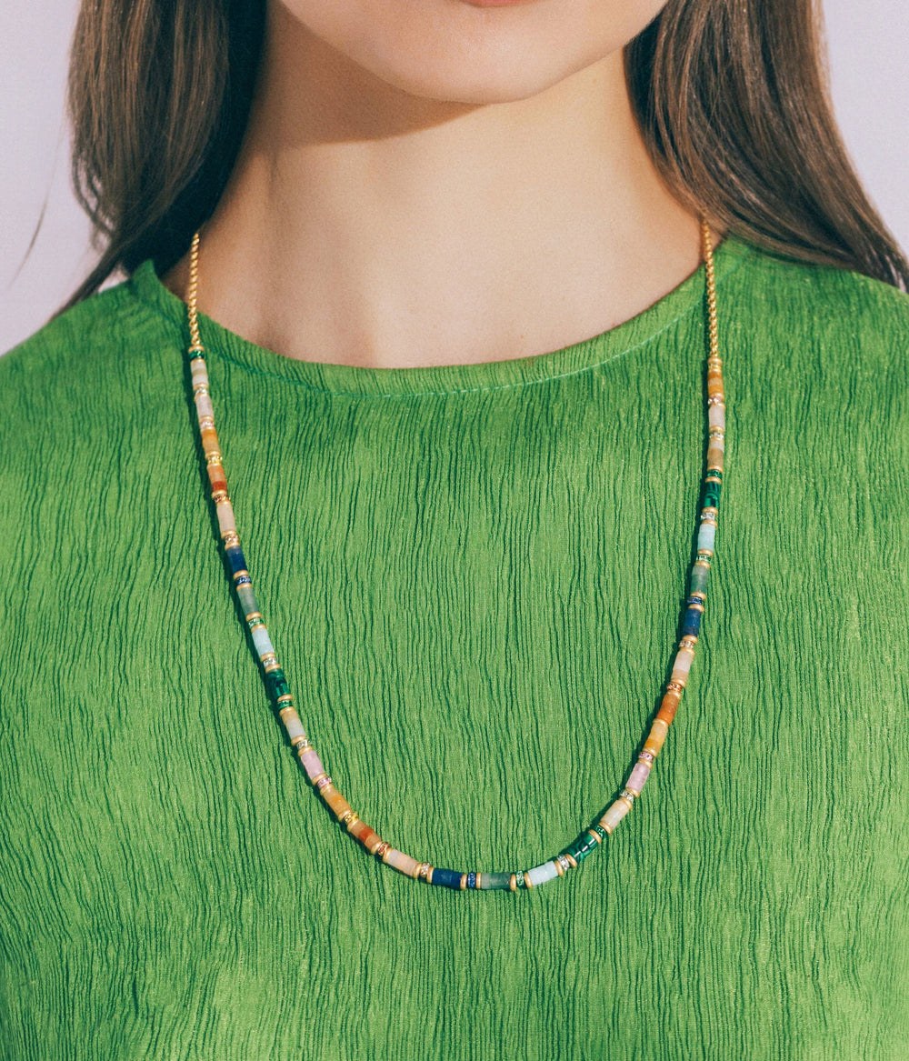 Front view of Rhodes Slider Necklace on model showing multicolored semi-precious stone slices and gold chain against a green textured top