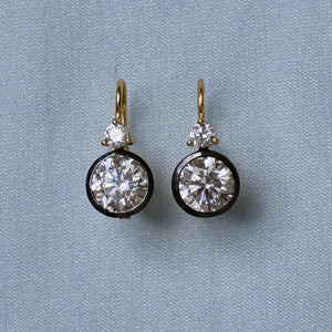 Front view of Rhodium Double Bezel Drop Earrings showcasing round faceted stones with a light blue textile background