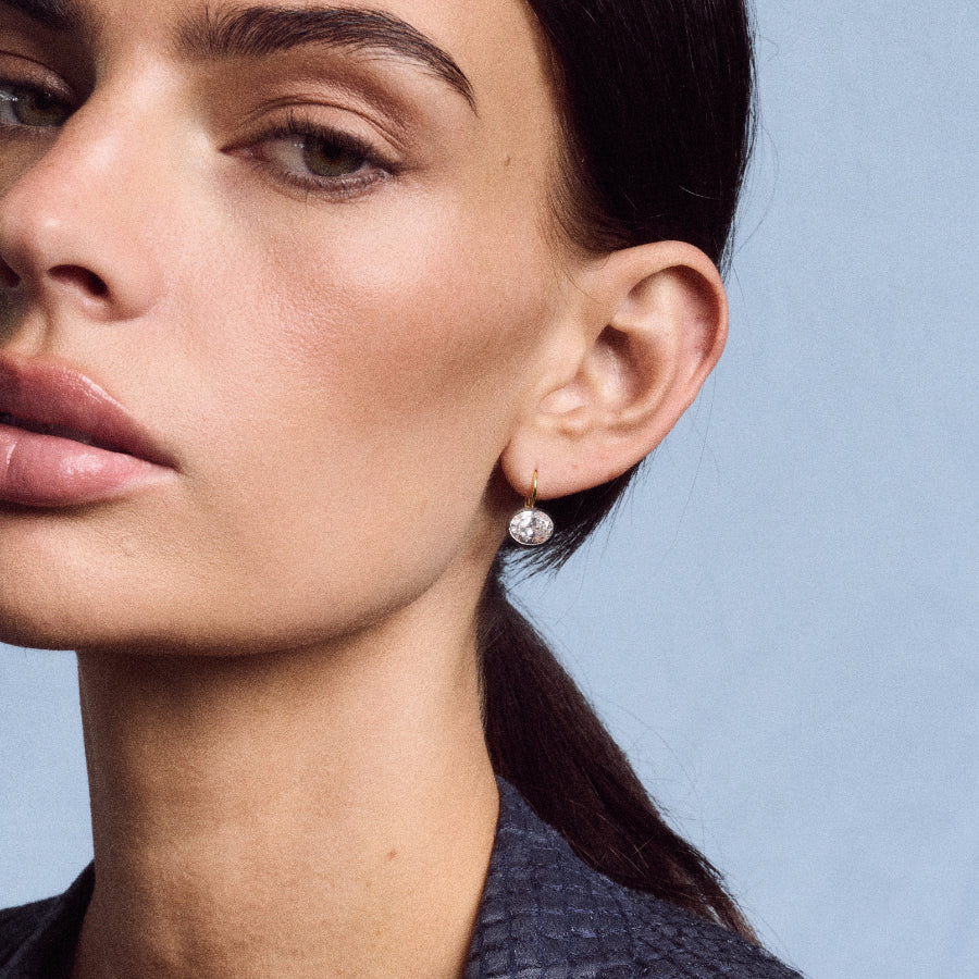 Side view of Rhodium Oval Bezel Drop Earrings showcasing an east-west oval stone in a dark rhodium bezel against blue-gray