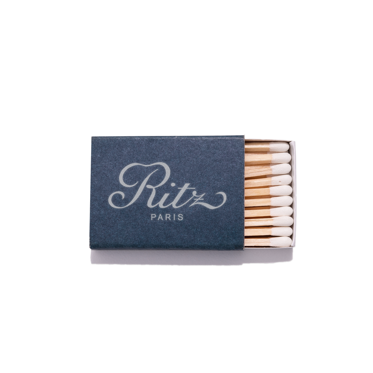 Top-down view of Ritz Paris matchbook showing navy cover with white script and exposed white-tipped matches on white background