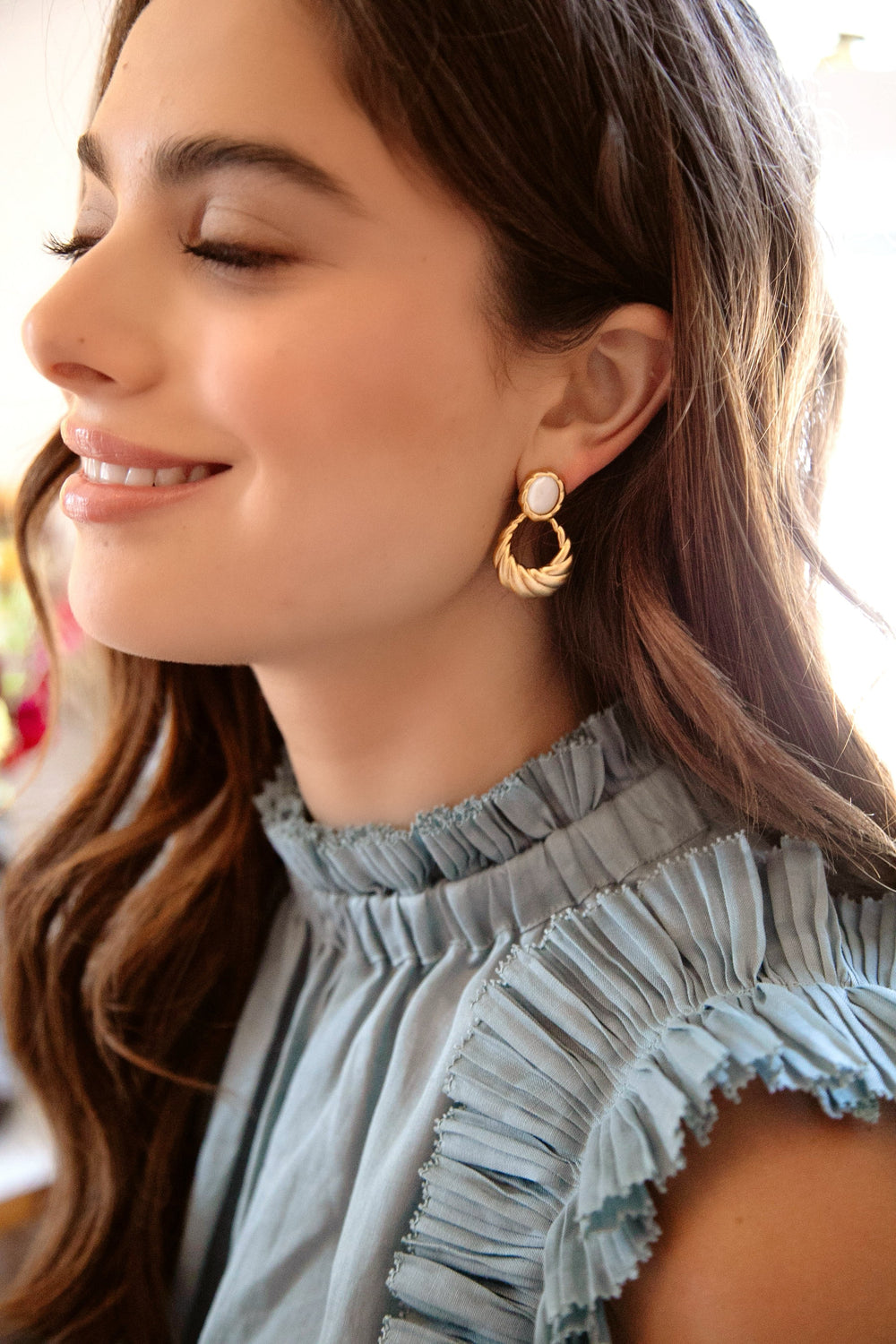 Close-up left profile of Roma Earrings showing gold-plated textured door-knocker hoops with mother-of-pearl cabochons on model