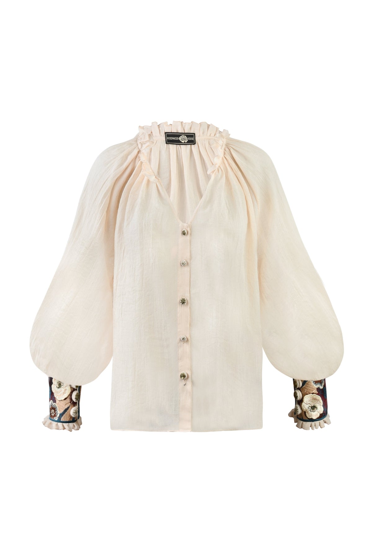 Front view of Pansy Blouse in creme showcasing gathered ruffle neckline, billowy puff sleeves and embroidered floral cuffs on white background
