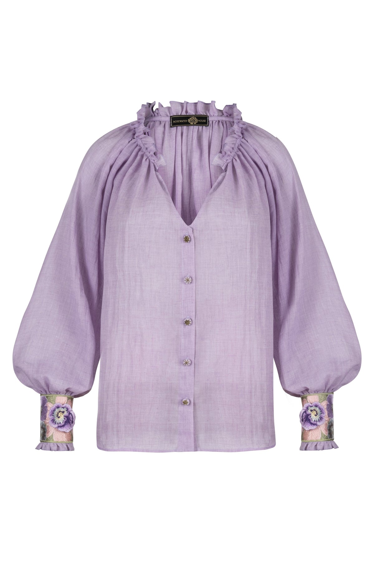 Front view of Pansy Blouse in lilac showing ruffled neckline, puff sleeves, embroidered floral cuffs and button front