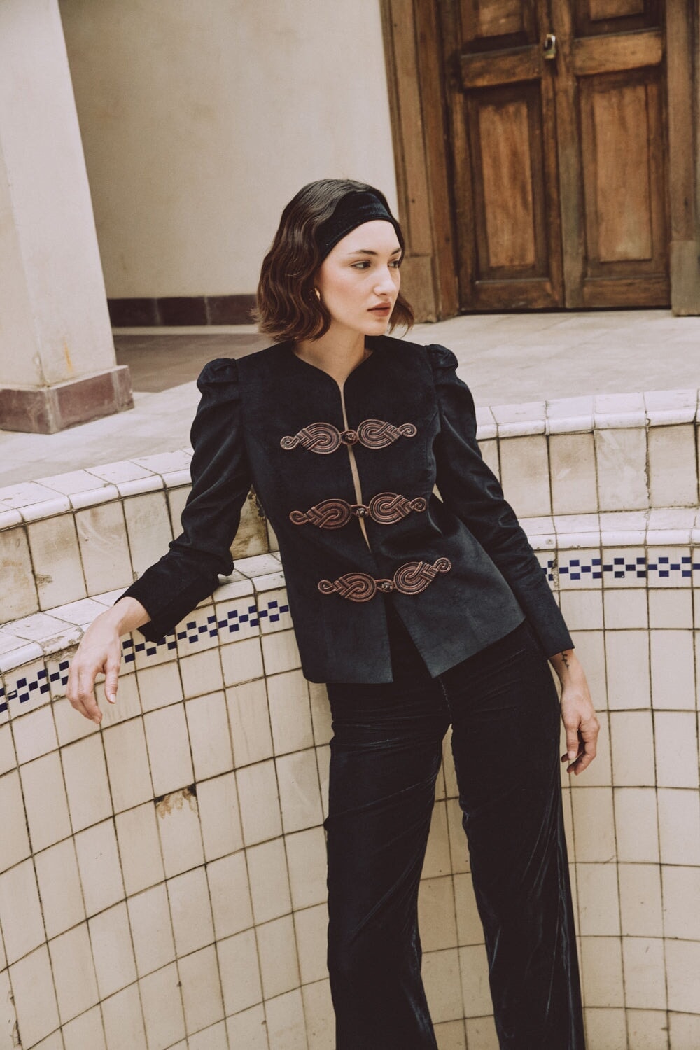 Three-quarter view of Mahtab straight-leg velvet pants in black showcasing high waist and subtle sheen against tiled wall