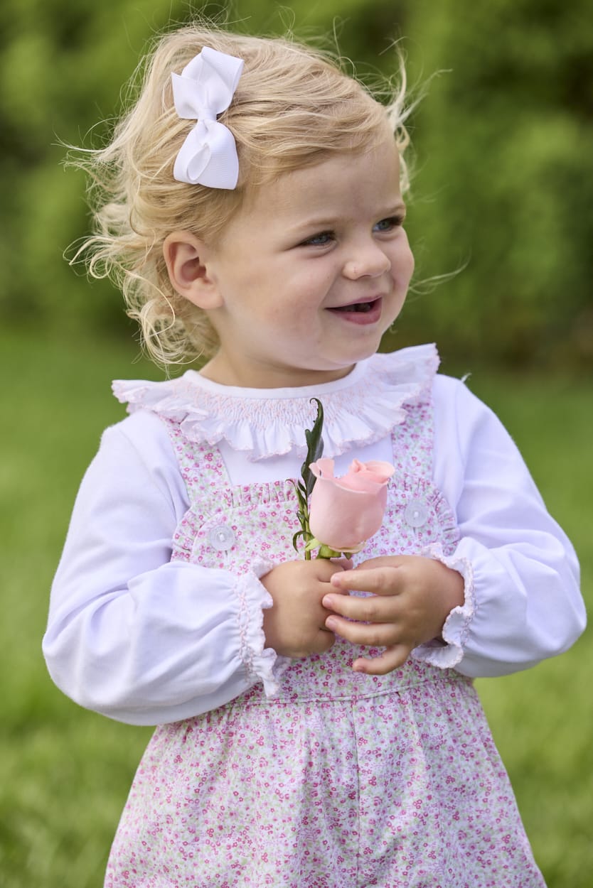 Little English traditional children's clothing.  Light pink and green floral overall with ruffle detailing layered over white knit smocked Madeline Blouse in light pink