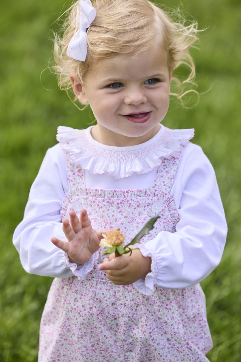 Little English traditional children's clothing.  Light pink and green floral overall with ruffle detailing layered over white knit smocked Madeline Blouse in light pink
