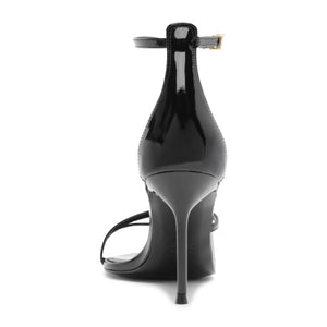 Rear view of black patent Tessa sandal showcasing stiletto heel and ankle buckle with white background