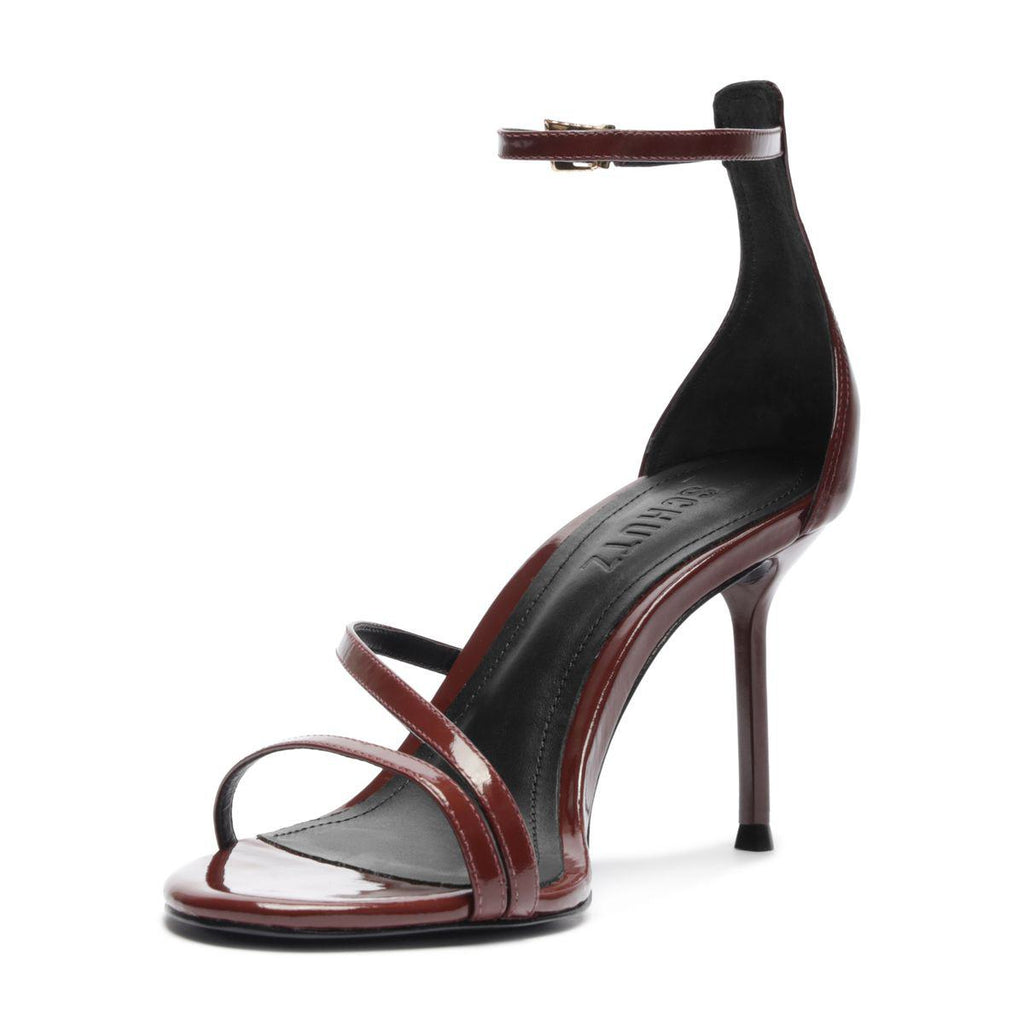 Three quarter view of Tessa Patent Sandal in Port Burgundy showcasing glossy patent leather straps and stiletto heel with a white background