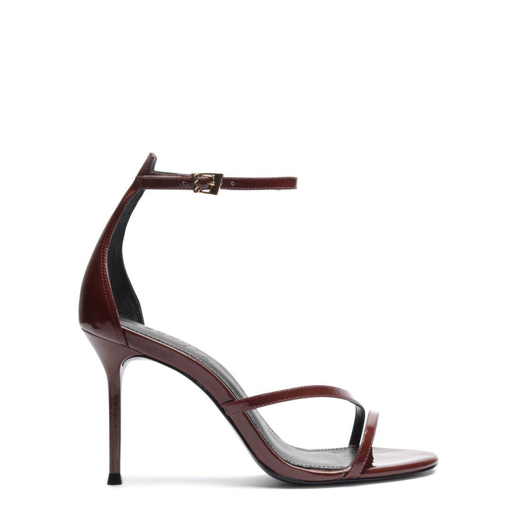 Side view of Tessa Patent Sandal showcasing glossy patent leather straps, stiletto heel, and buckle closure with a white background