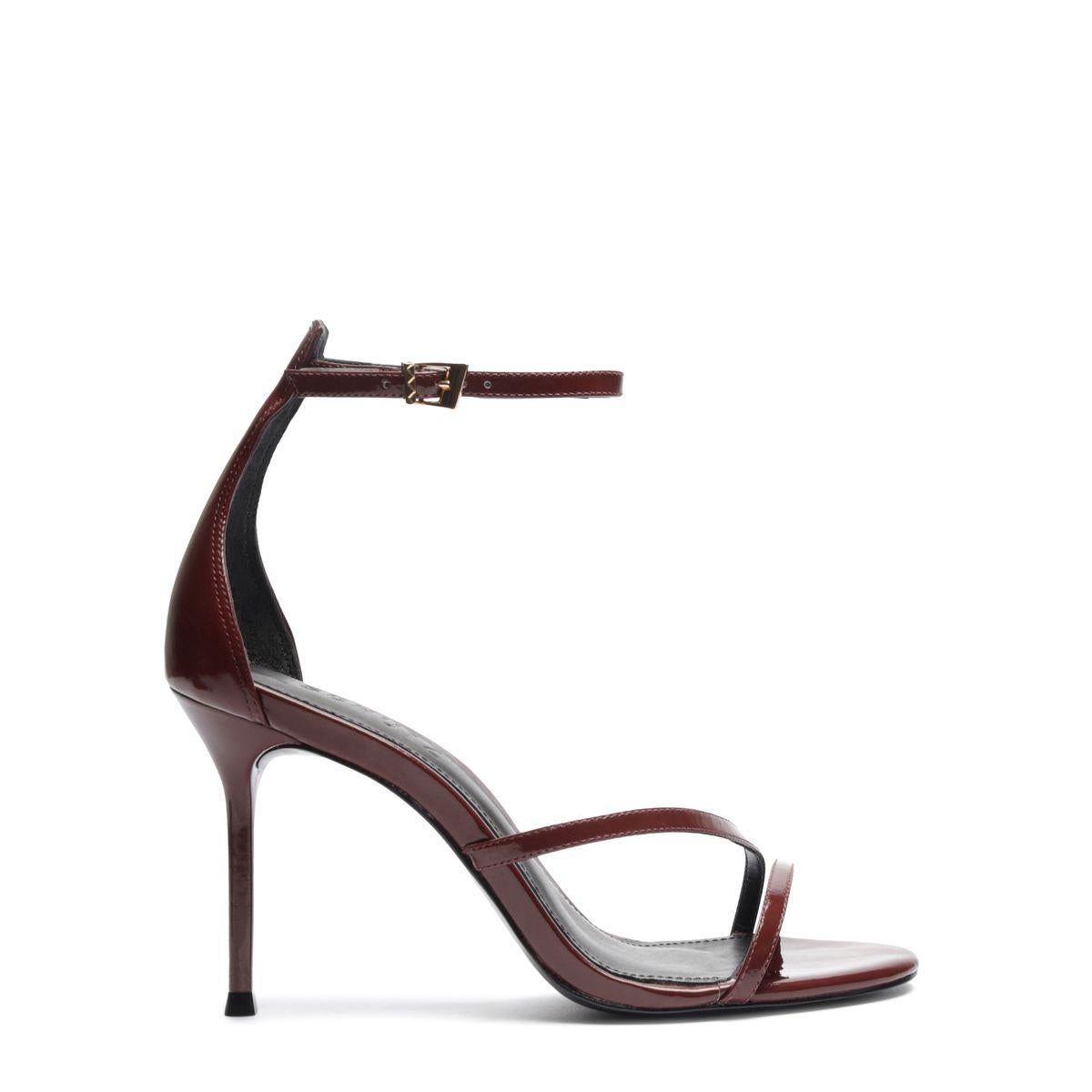 Side view of Tessa Patent Sandal showcasing glossy patent leather straps, stiletto heel, and buckle closure with a white background