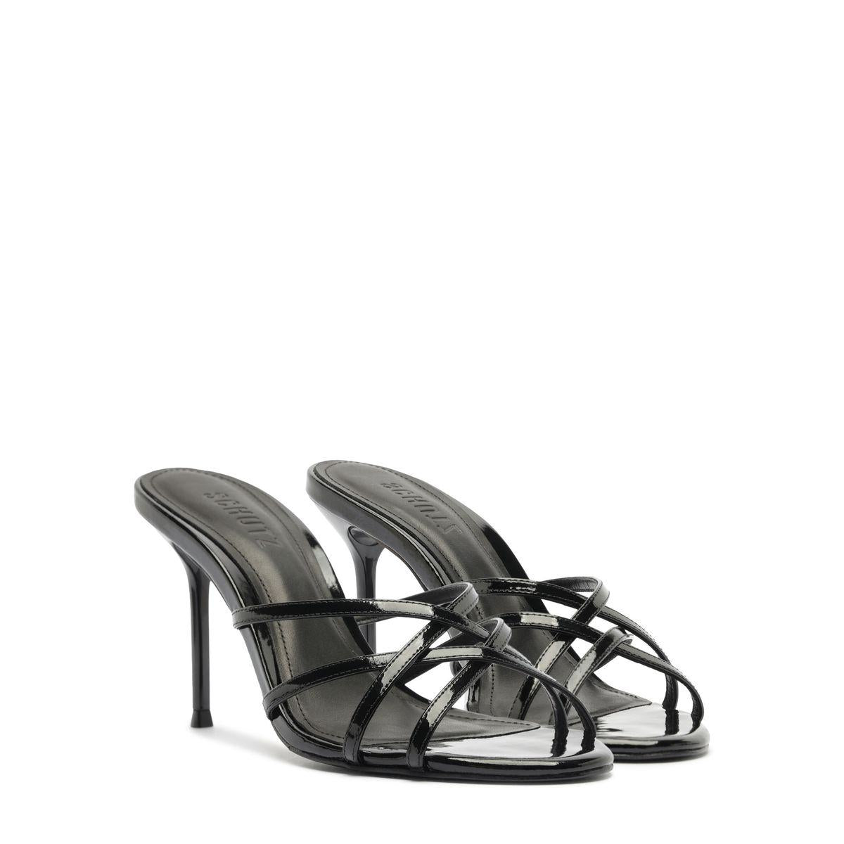 Front three-quarter view of Marion Patent Sandal in Black showcasing delicate patent leather straps and stiletto heel with white background