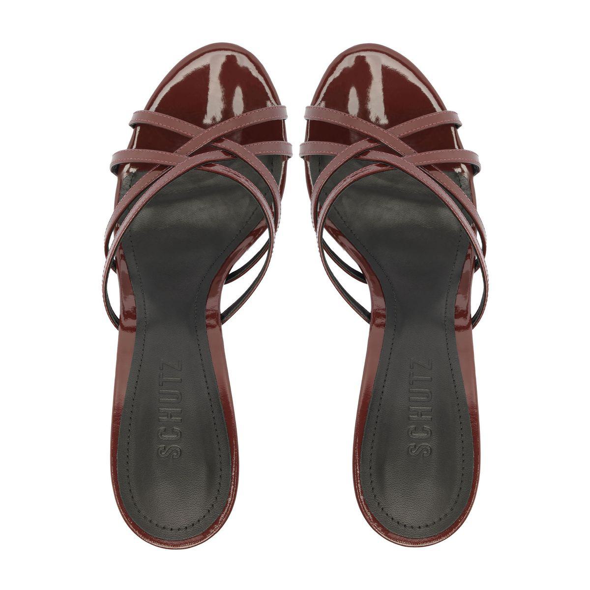 Top view of Marion Patent Sandal in Port Burgundy showcasing crisscross patent straps and dark footbeds on a white background
