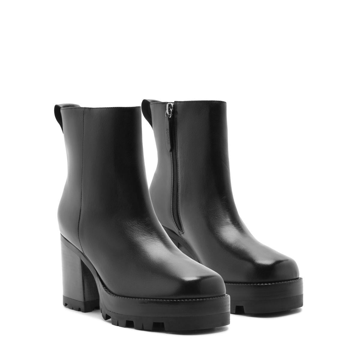 Front three-quarter view of 240 leather booties in black showcasing side zippers, block heels, and lug soles on a white background