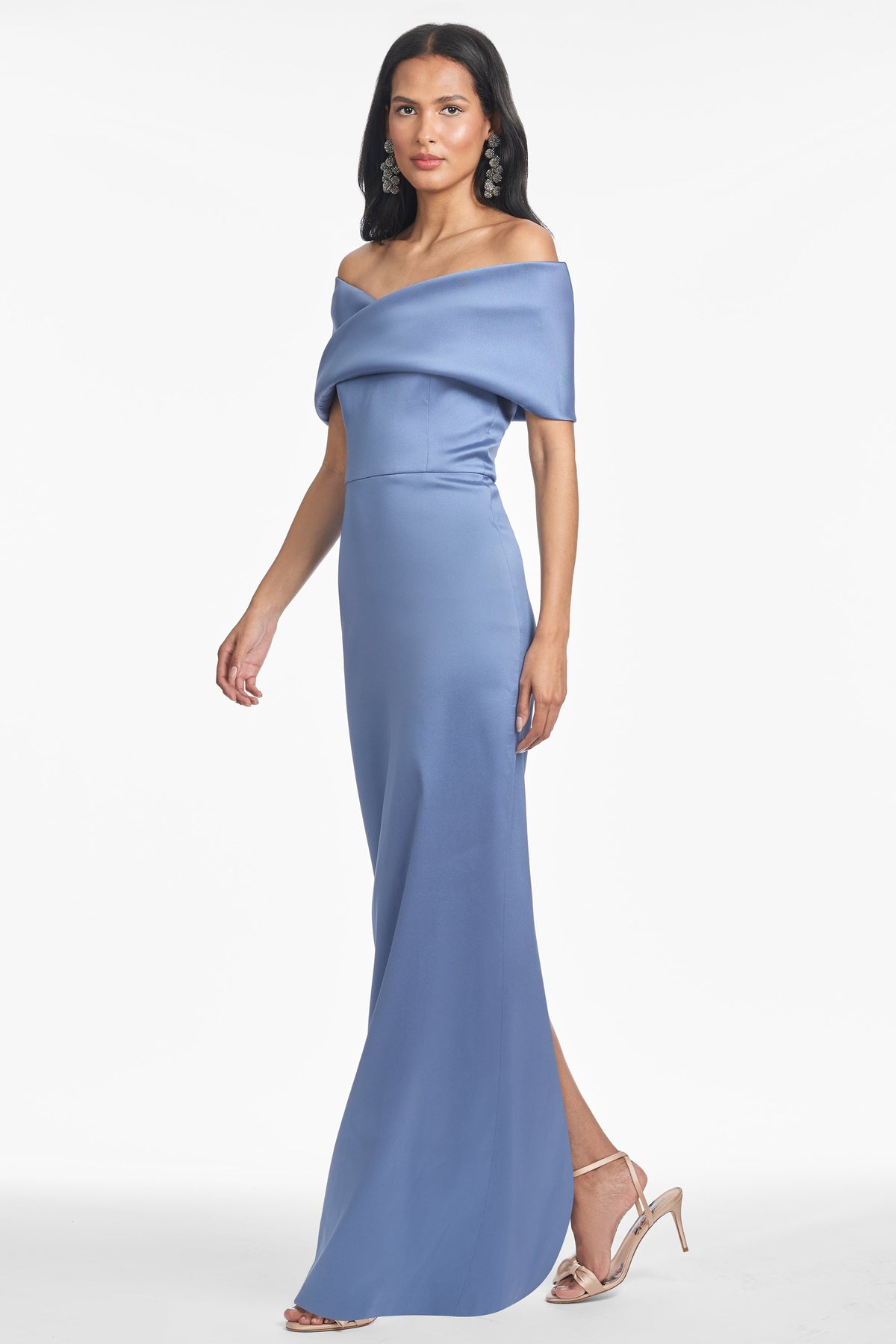 Side view of Viveca Gown in twilight showcasing off-shoulder twist neckline and slim full-length skirt on white background