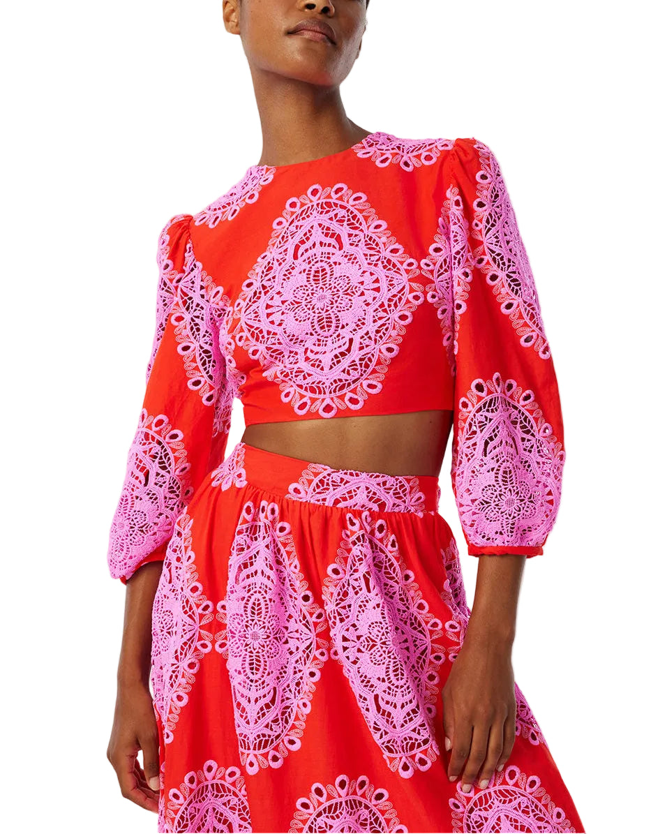 Three-quarter view of Rhea lace top in red with pink lace medallions, cropped style and puff sleeves on model