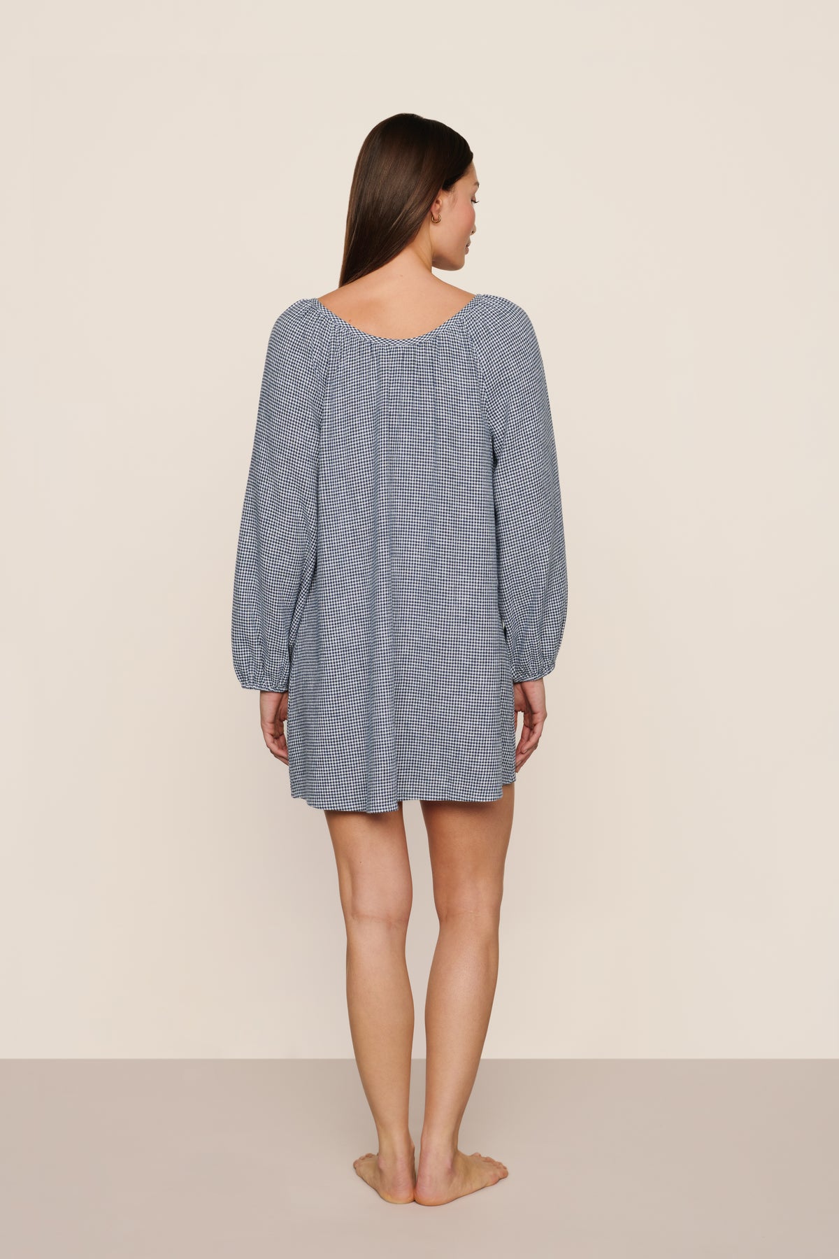 Back view of linen blend short dress in gingham white/navy showing babydoll silhouette and balloon sleeves with elastic cuffs on neutral background
