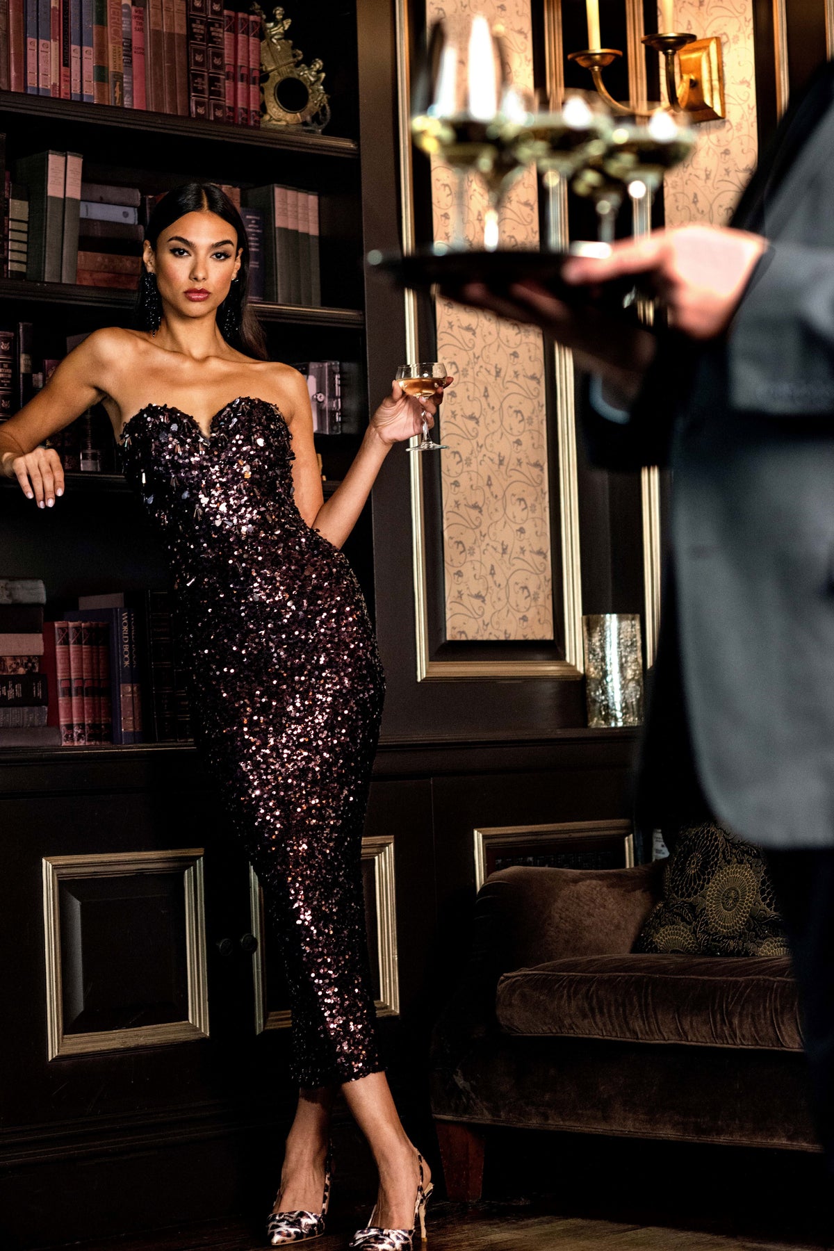 Front view of Babe Dress in Plum on a model, showcasing its strapless sweetheart neckline and plum sequins in a library setting