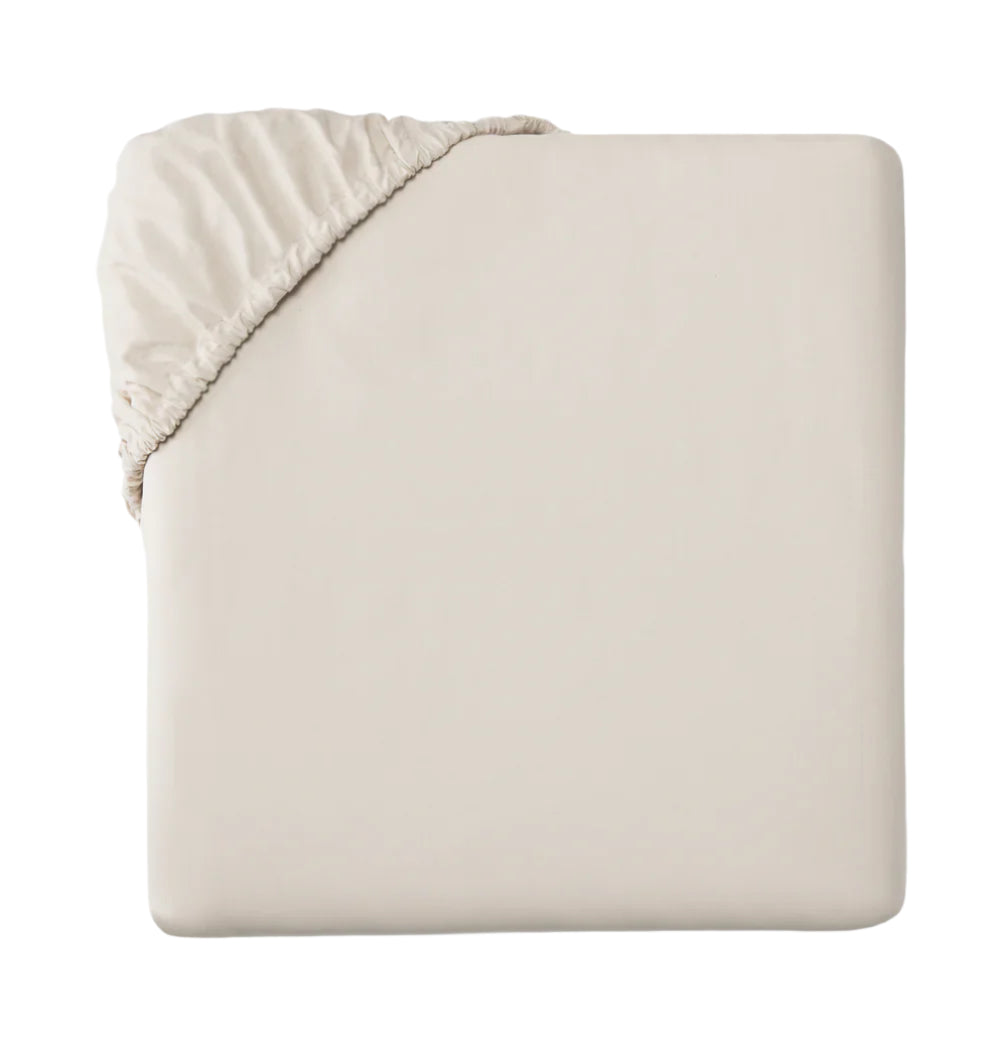 Top-down view of Celeste fitted sheet in bone showing elastic corner and smooth fitted surface on white background