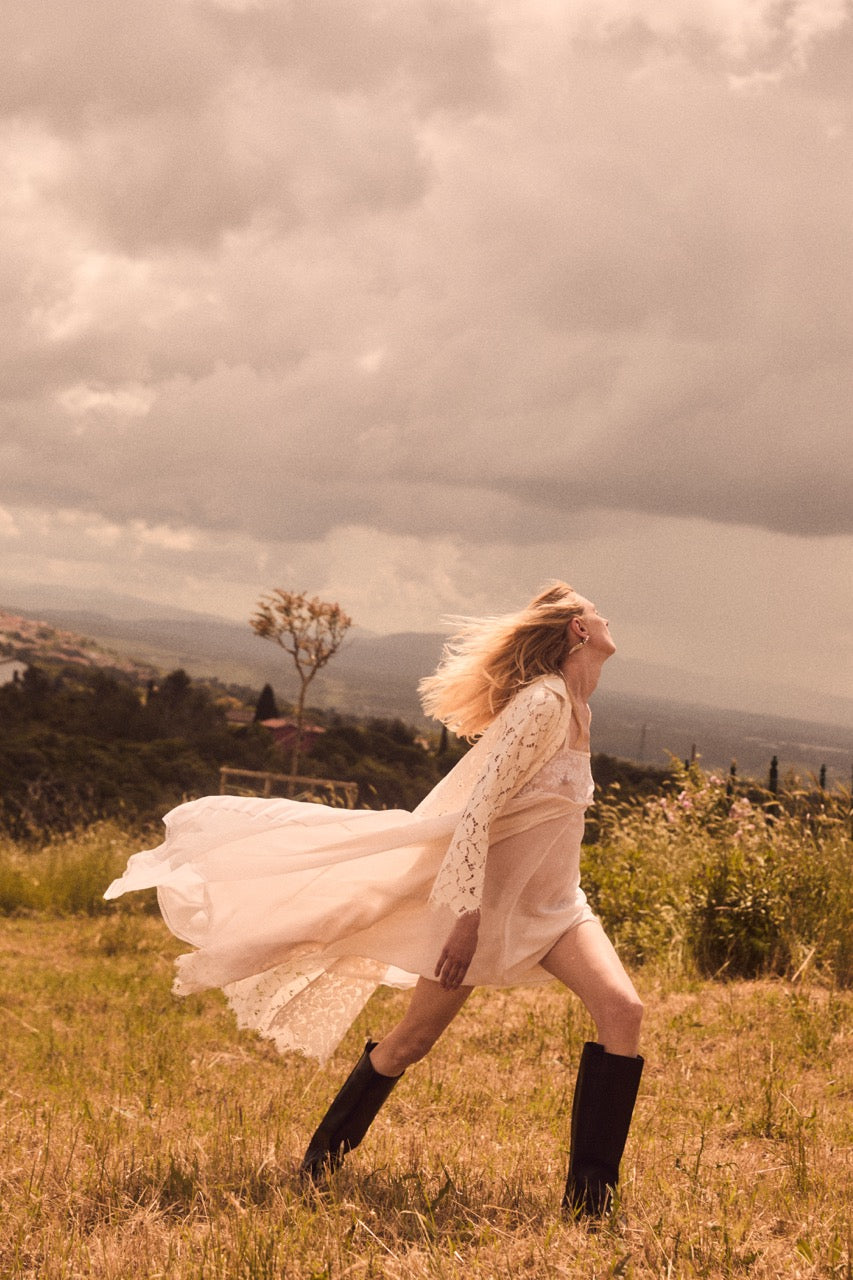 Model wearing Malvina nightgown in Sunrise Georgette running in a grassy field, flowing silhouette and lace trim
