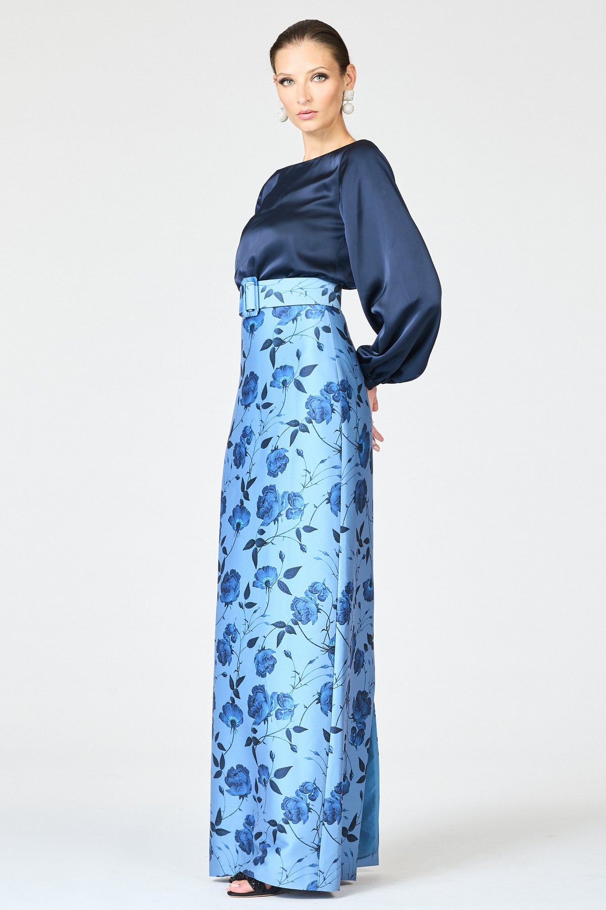 Three-quarter view of Astor Gown in Wild Steel Roses showing navy satin bodice, gathered sleeves, floral skirt, and belt