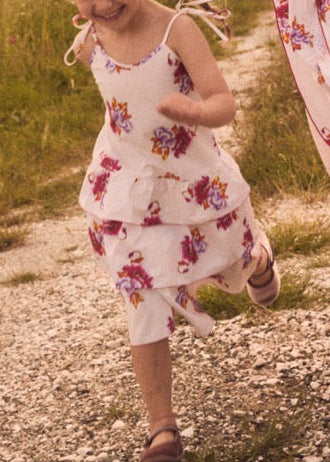 Front view of Girl’s Evangeline Dress in Mortella on a child, showcasing spaghetti straps, tiered gathered skirt, and loose fit in an outdoor setting
